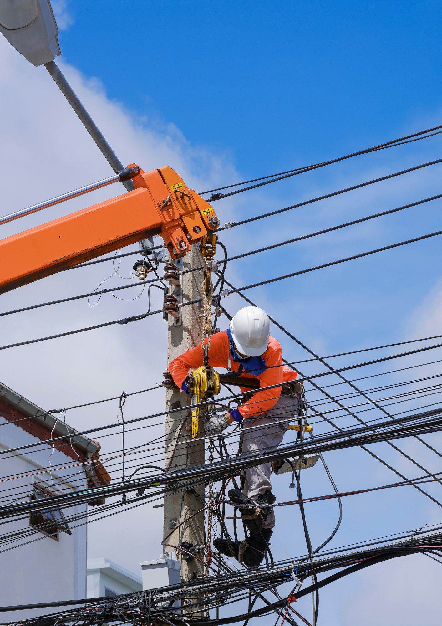 Electrician with crane truck is installing electrical transmission on electric power pole