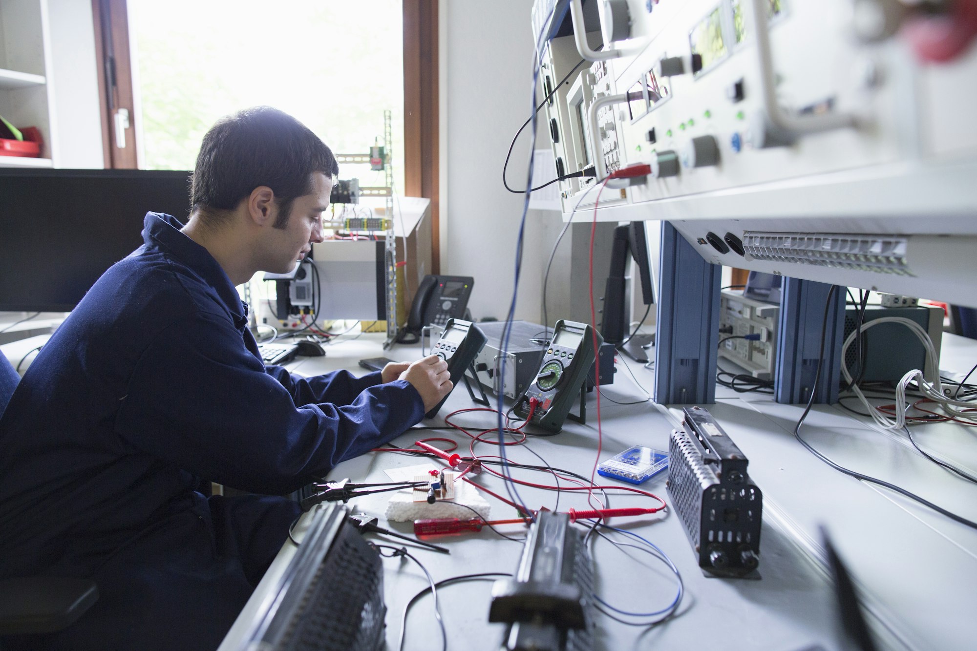 Male electrician repairing electronic equipment in workshop