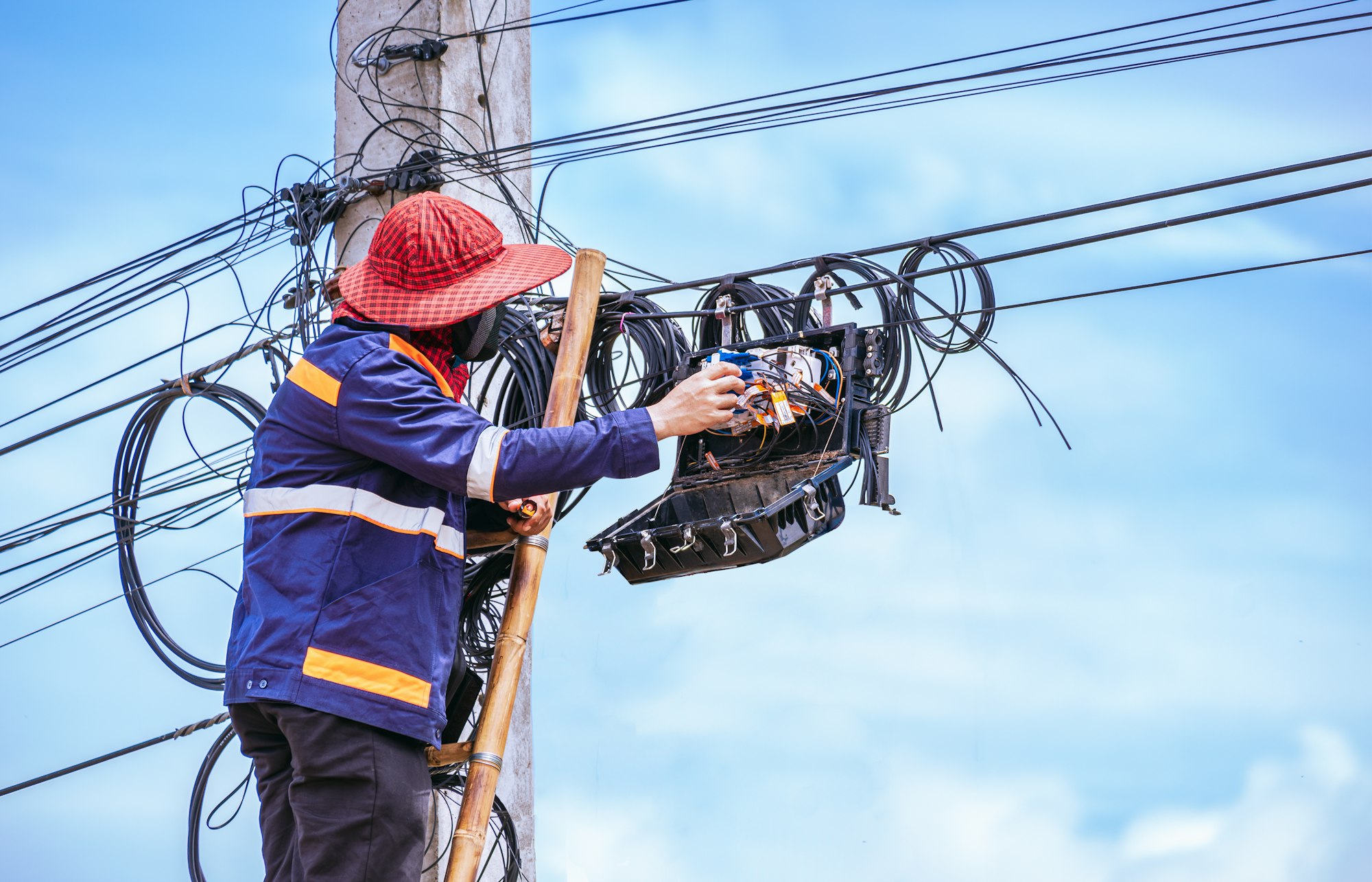 Technician is repairing internet connection system in splitter box on electricity pole